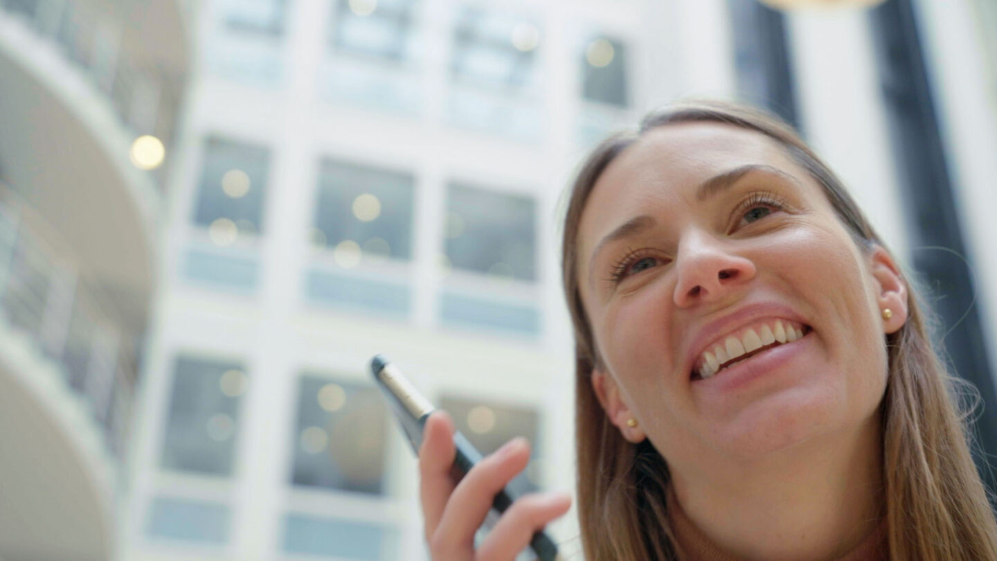Woman employee at H&M Group offices holding a phone and smiling