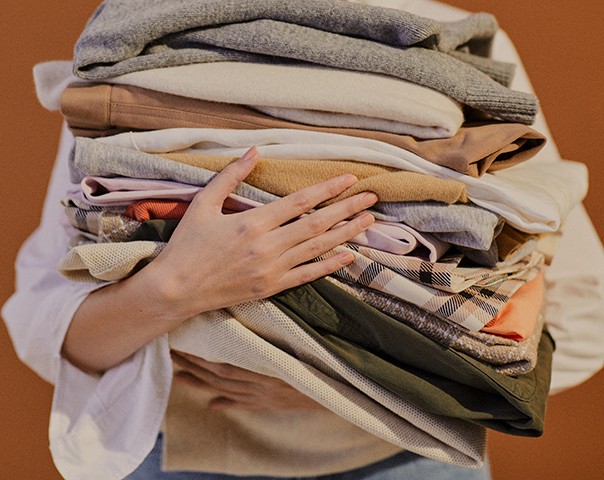 View of hands holding a pile of folded clothes