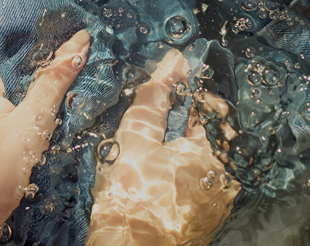A view of hands washing denim in water