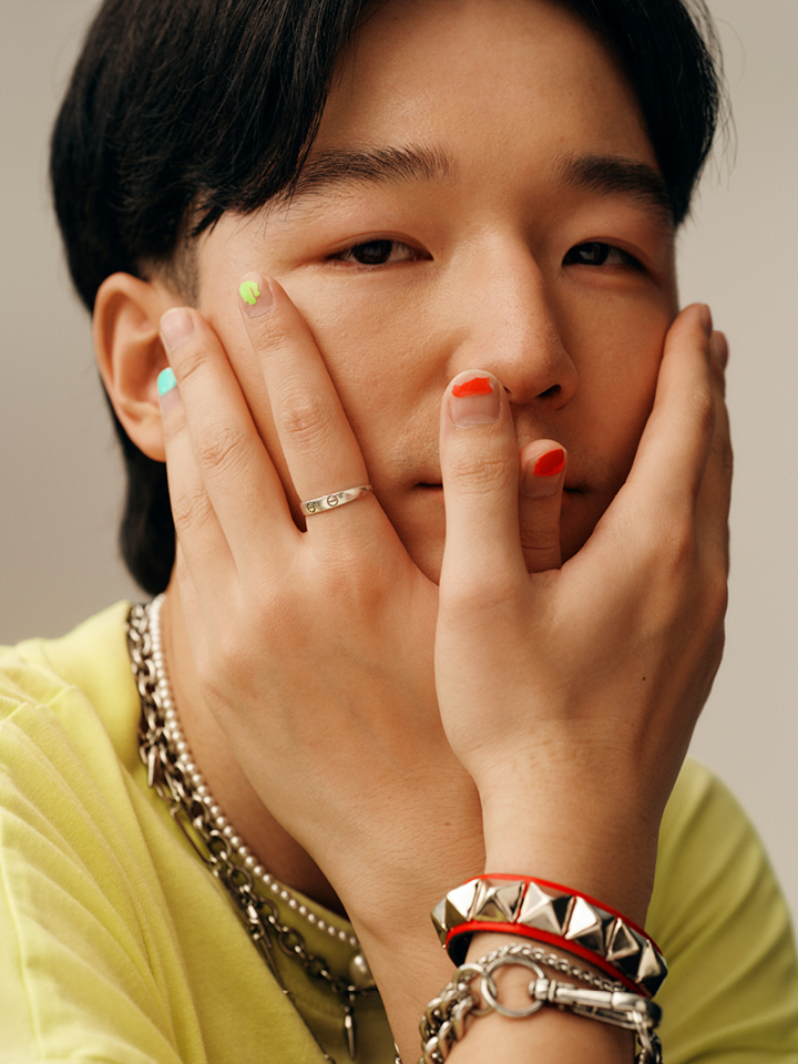 Tech employee wearing a yellow t-shirt, silver jewelry, with hands covering their face.