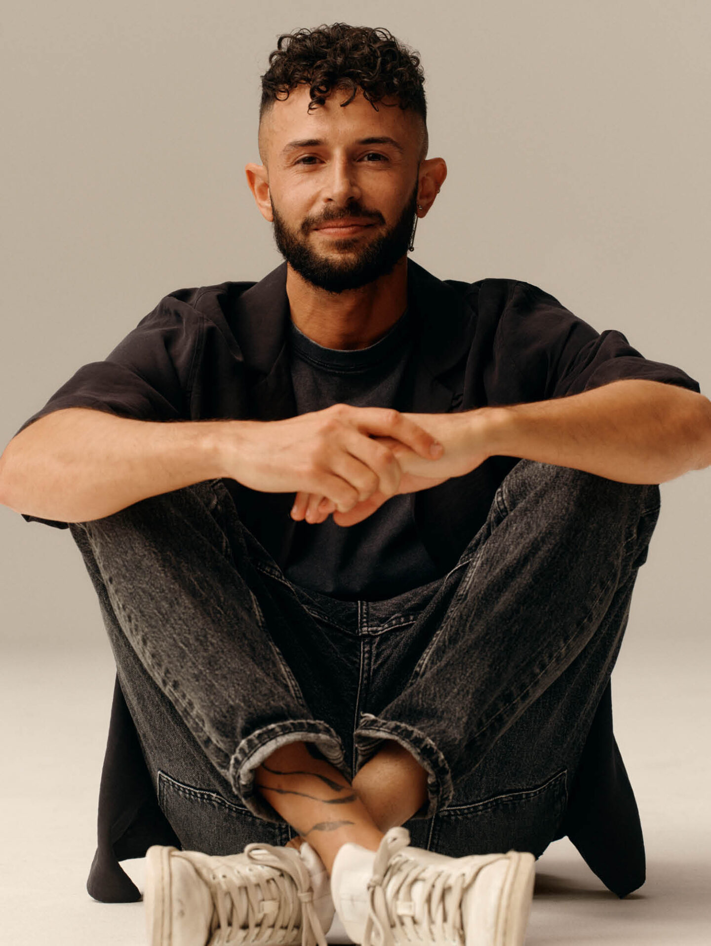 Tommasso, Store Manager at H&M, sitting on the floor in jeans and a t-shirt.