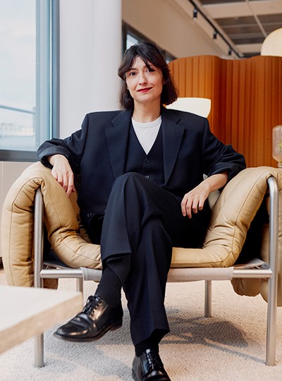 Women dressed in a suit sitting in a comfortable chair and looking at the camera