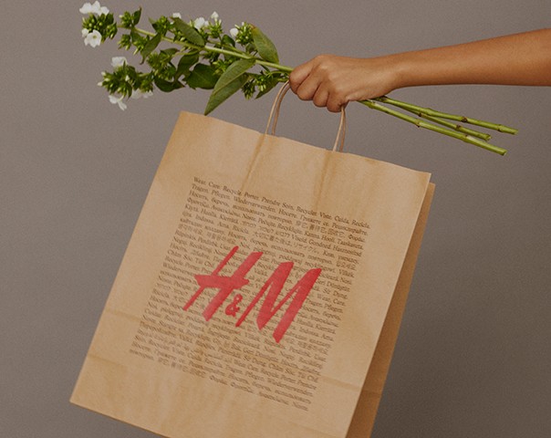 Vaizdas į ranką, laikančią gėles ir popierinį maišelį