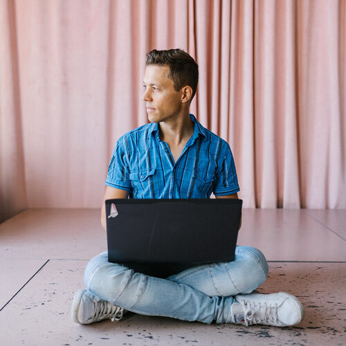 Vyras sėdi ant grindų su nešiojamuoju kompiuteriu