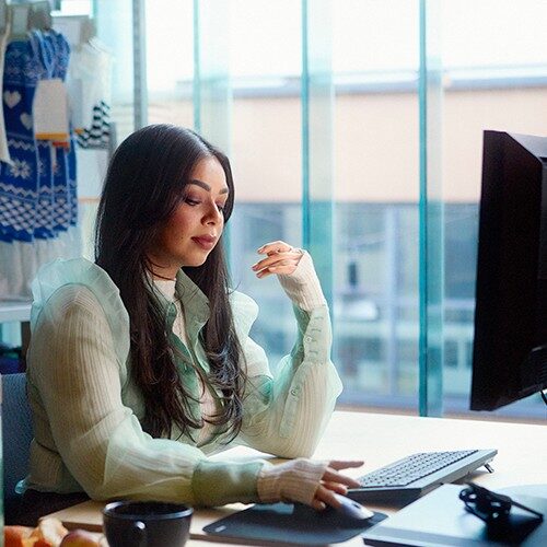 Femme assise devant un ordinateur en train de taper