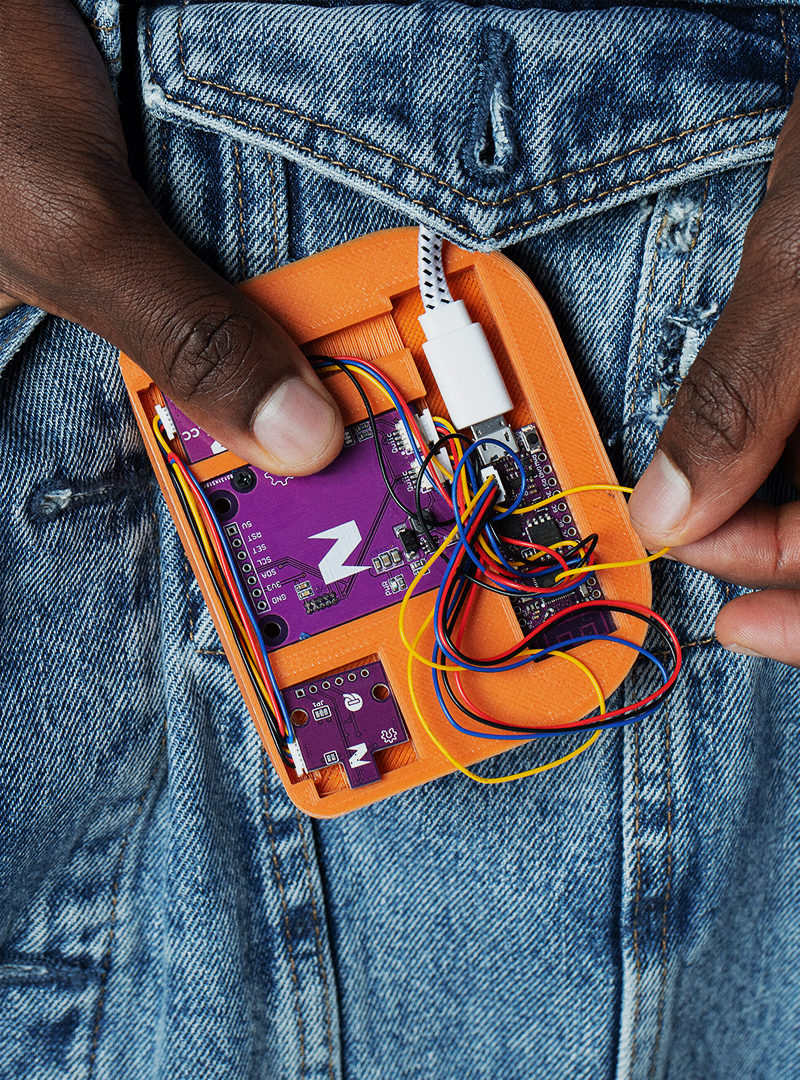 Hands holding an orange electric open device over a jeans jacket