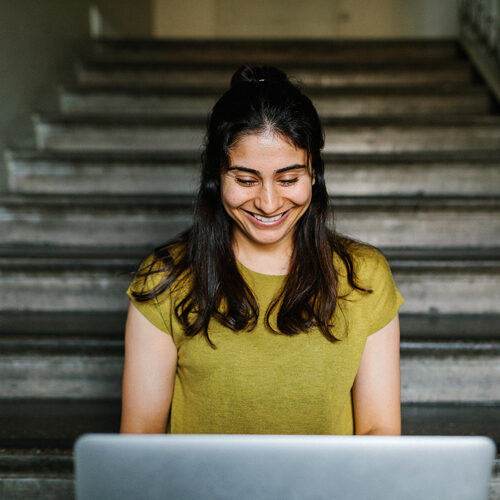 En kvinna ler och tittar ner på sin dator