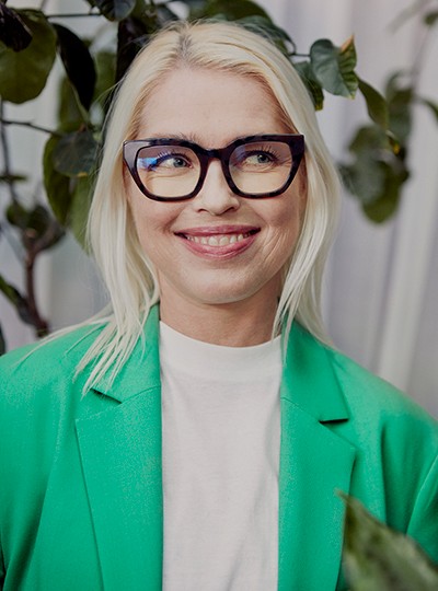 Une collaboratrice portant des lunettes, souriant off camera