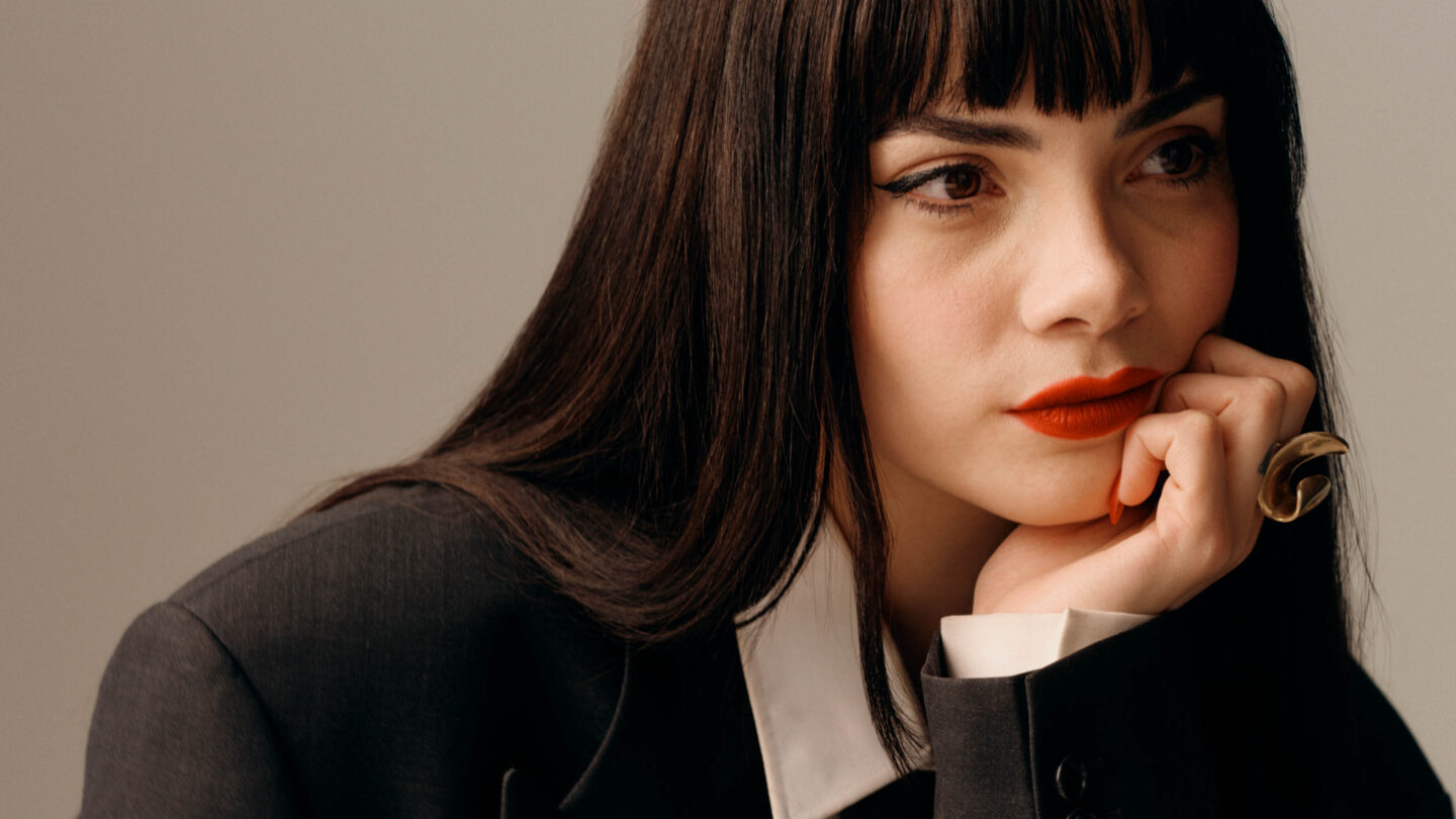 Portrait of a woman wearing a suit and red lipstick.